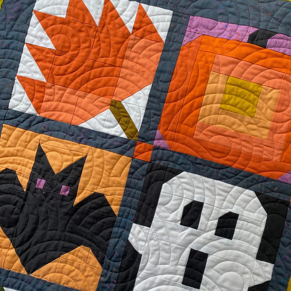Quilt with Halloween-themed patterns including a cat, ghost, and jack-o'-lantern.